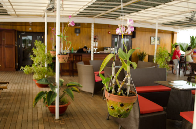 The outdoor Sun Deck, with its covered awning, hanging plants and comfortable loungers, is a great place to watch the Mekong drift by. Photo © 2013 Aaron Saunders