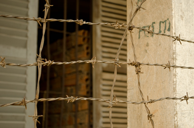 Razor wire was added to the former highschool in 1975 when it was taken over by Pol Pot's Khmer Rouge. Photo © 2013 Aaron Saunders