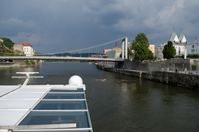 Emerald Star departs Passau under increasingly dark skies. It never rained, but the thunder was very pronounced. Note the windows in the foreground for Emerald Star's swimming pool. Photo © 2014 Aaron Saunders