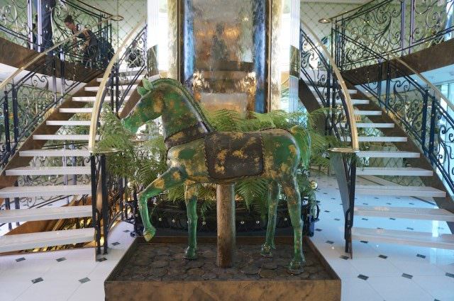 Where some of the $2 million spent on original art surely went: The atrium with its Murano glass horse and waterfall background and stairs descending on both sides. © 2014 Ralph Grizzle